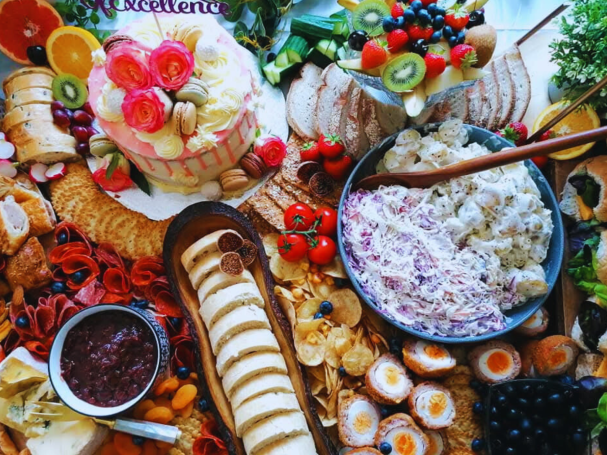 A vibrant spread of assorted meats, cheeses, fruits, and a decorative cake.