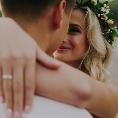 A couple embracing, smiling, with the woman wearing a flower crown.