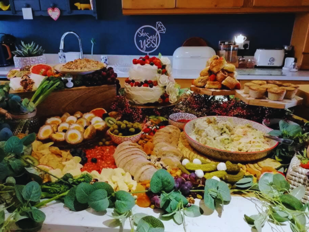 A colourful spread of fruits, cheeses, pastries, and decorative greenery on a table.