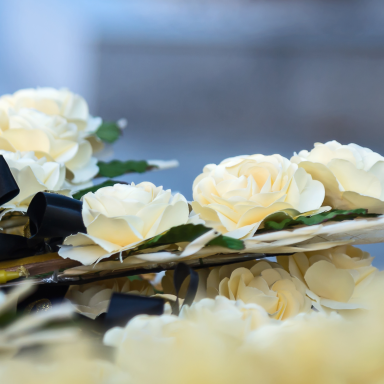 A bouquet of pale yellow roses arranged with dark ribbon accents.