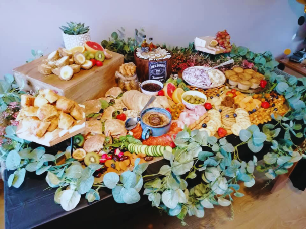 A vibrant spread of assorted breads, fruits, cheeses, and dips on a decorative table.