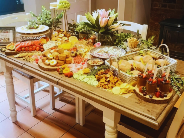 A beautifully arranged table filled with various foods, fruits, and decorative plants.